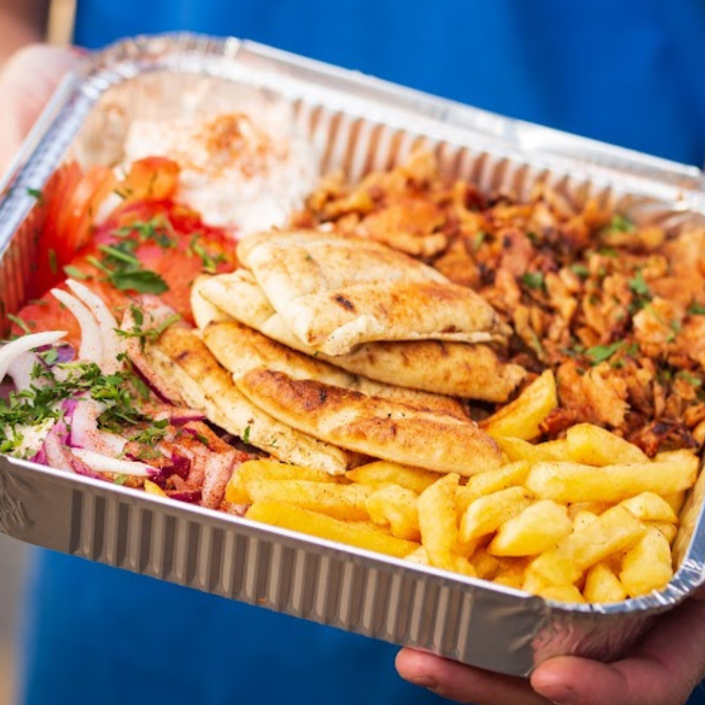 Greek pork gyros plate with chips, fresh salad, warm pita bread and tzatziki.